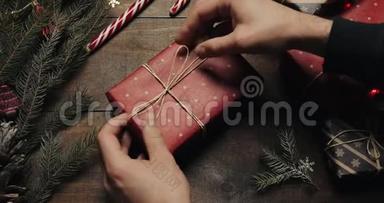 男子手把礼品盒用<strong>装饰线</strong>绑好后用红纸包在木桌上，准备